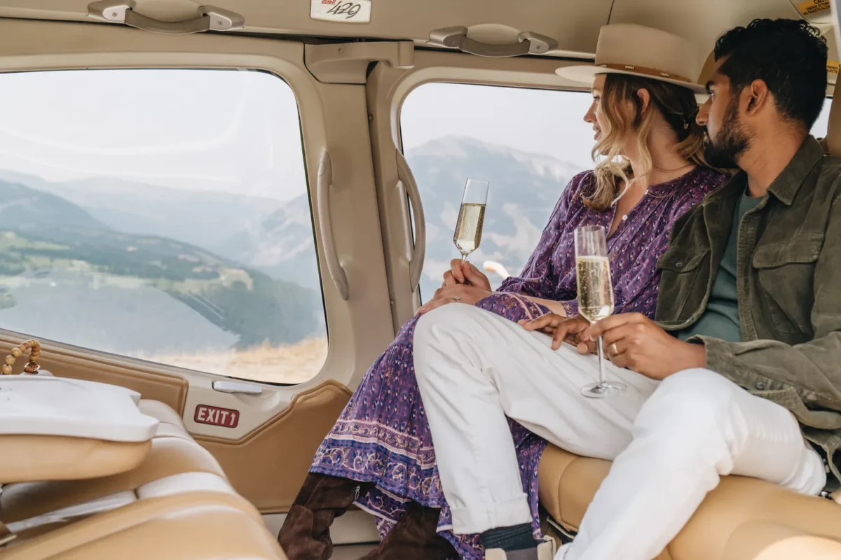 Couple enjoying champagne while looking at the view from a helicopter. Perfect for a Montana wedding venue.