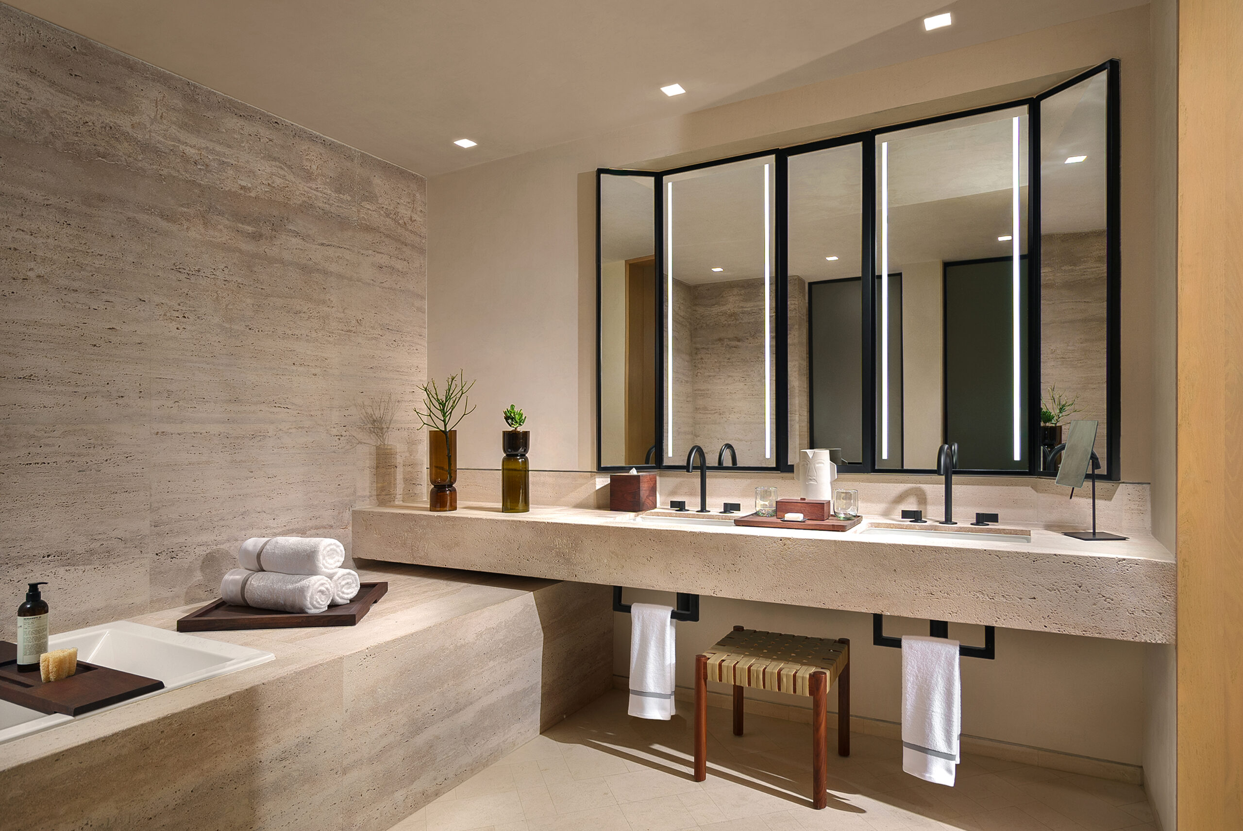 Park Hyatt Los Cabos bathroom with travertine walls, stone vanity, and black framed mirrors.