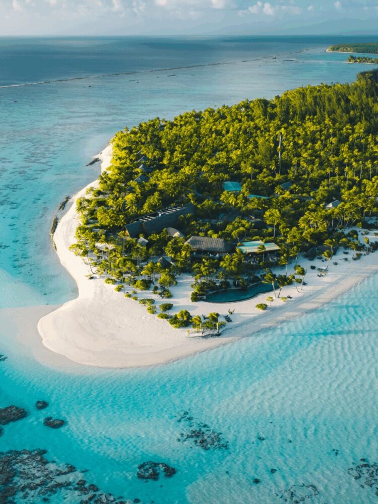 Aerial view of a tropical island with white sand beaches, turquoise water, and lush greenery.