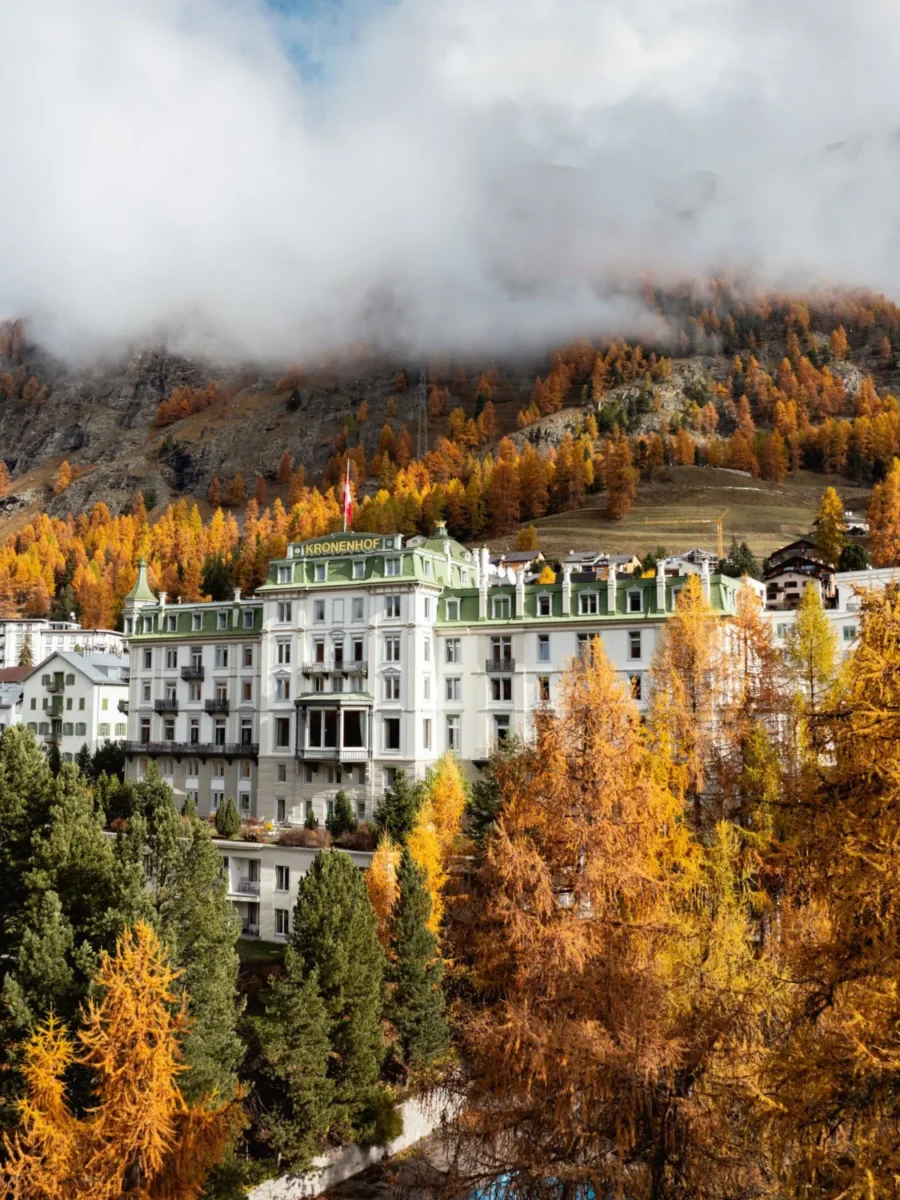 Grand hotel in St. Moritz, Switzerland, surrounded by autumn trees.