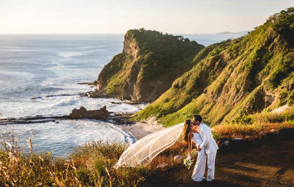 Rancho Santana wedding: Bride and groom kissing with a veil blowing in the wind, overlooking the ocean.