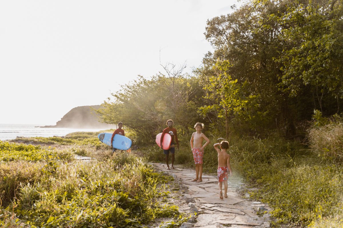 Family walking on a coastal path at Rancho Santana with surfboards