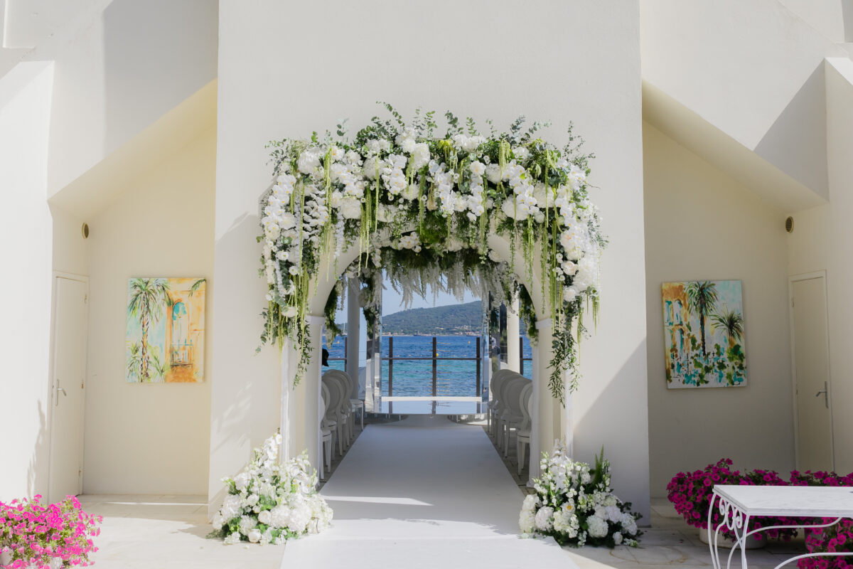 Luxury wedding in Saint-Tropez: Floral archway frames ocean view at COMO Le Beauvallon.