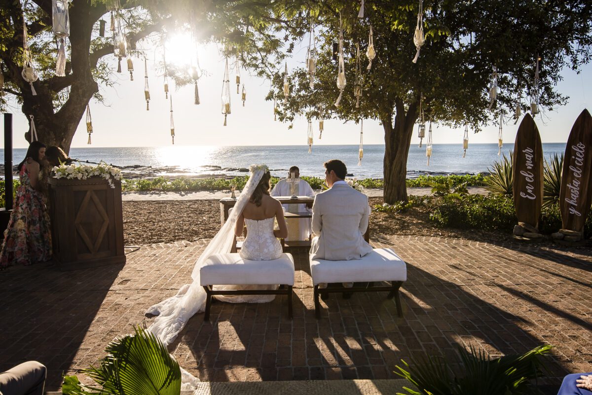 Rancho Santana wedding ceremony on the beach with bride, groom, and officiant under trees.