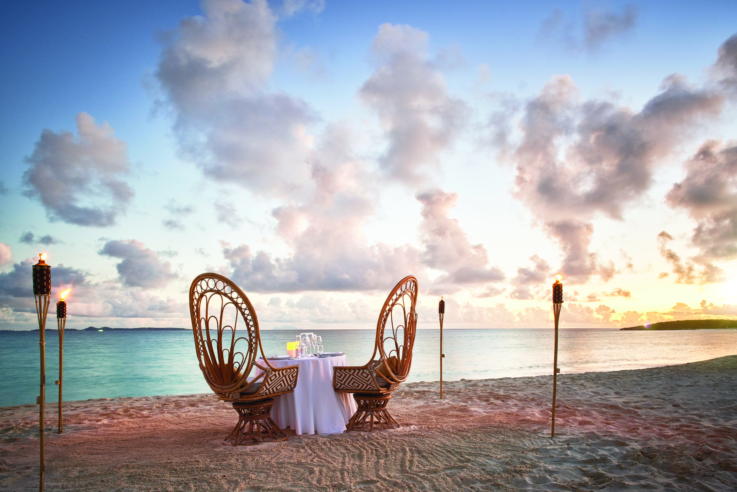 Romantic beachside dinner setup at sunset for luxury honeymoons 2026