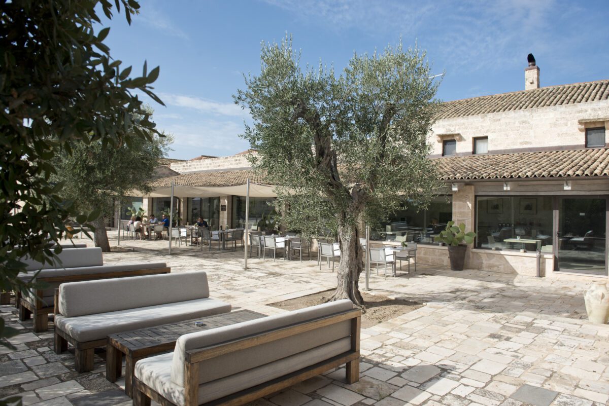 Relais Histò Hotel & SPA courtyard with olive trees, outdoor seating, and stone architecture.
