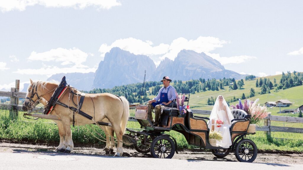 Bride in horse-drawn carriage with mountain backdrop