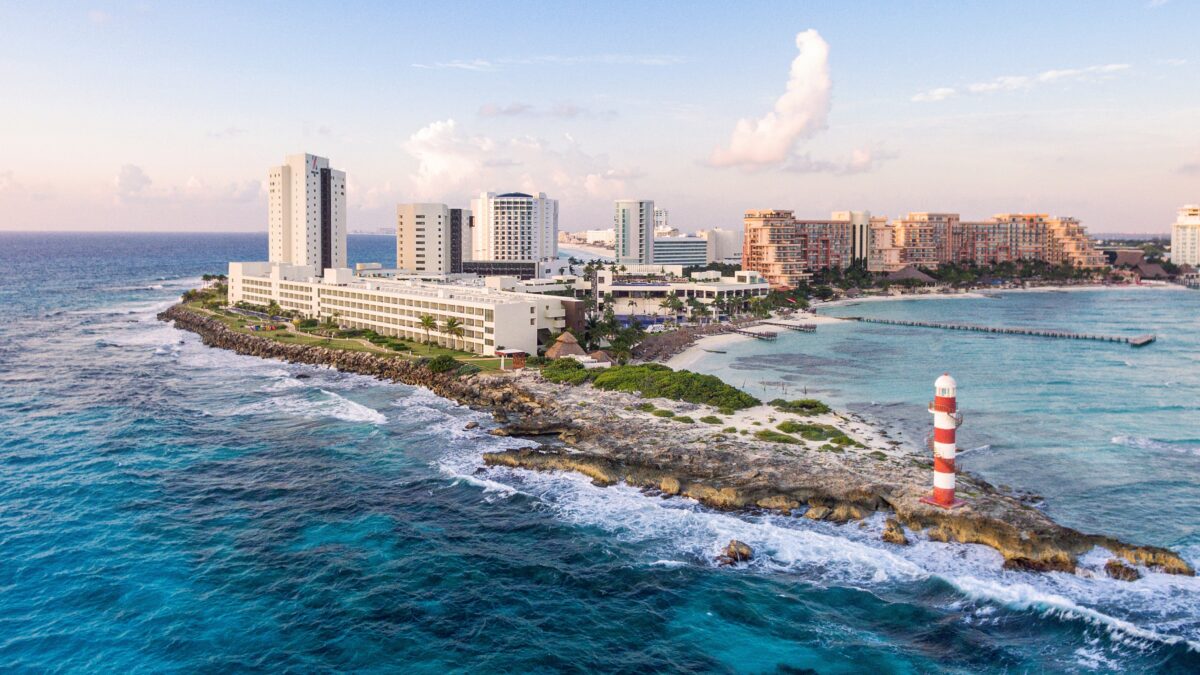 Hyatt Ziva Cancún aerial view featuring the beach, resort buildings, and a red and white lighthouse.