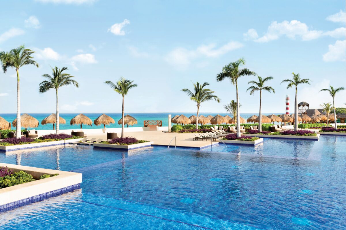 Hyatt Ziva Cancun pool view with palm trees and beach umbrellas.