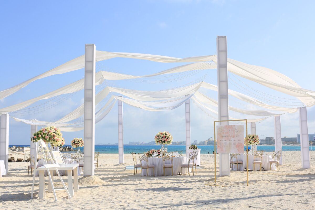 Luxury wedding venue in Cancun at Hyatt Ziva. Beach wedding reception setup with white decor and floral centerpieces.
