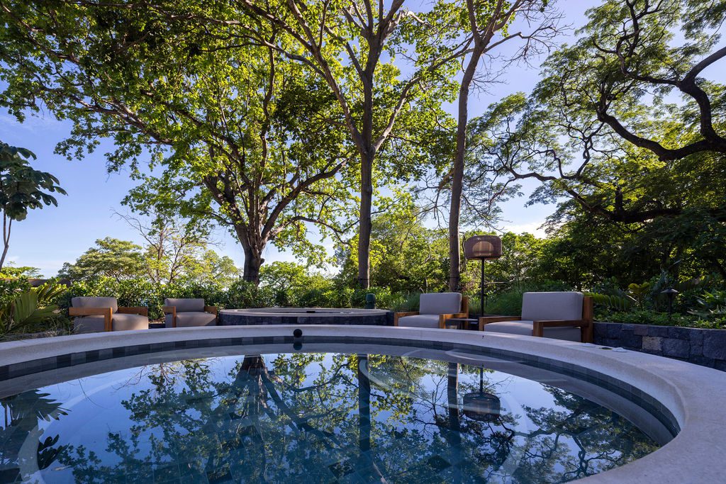 Waldorf Astoria Costa Rica: Circular pool reflecting trees and sky, surrounded by lounge chairs.
