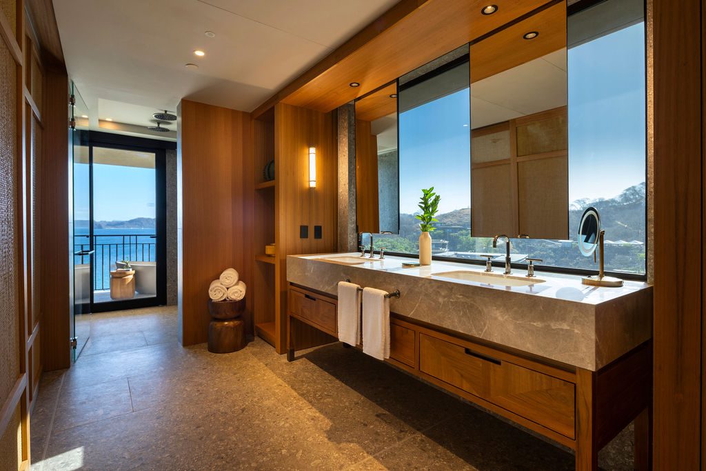 Waldorf Astoria Costa Rica bathroom with dual sinks, wood cabinets, and a stunning ocean view.