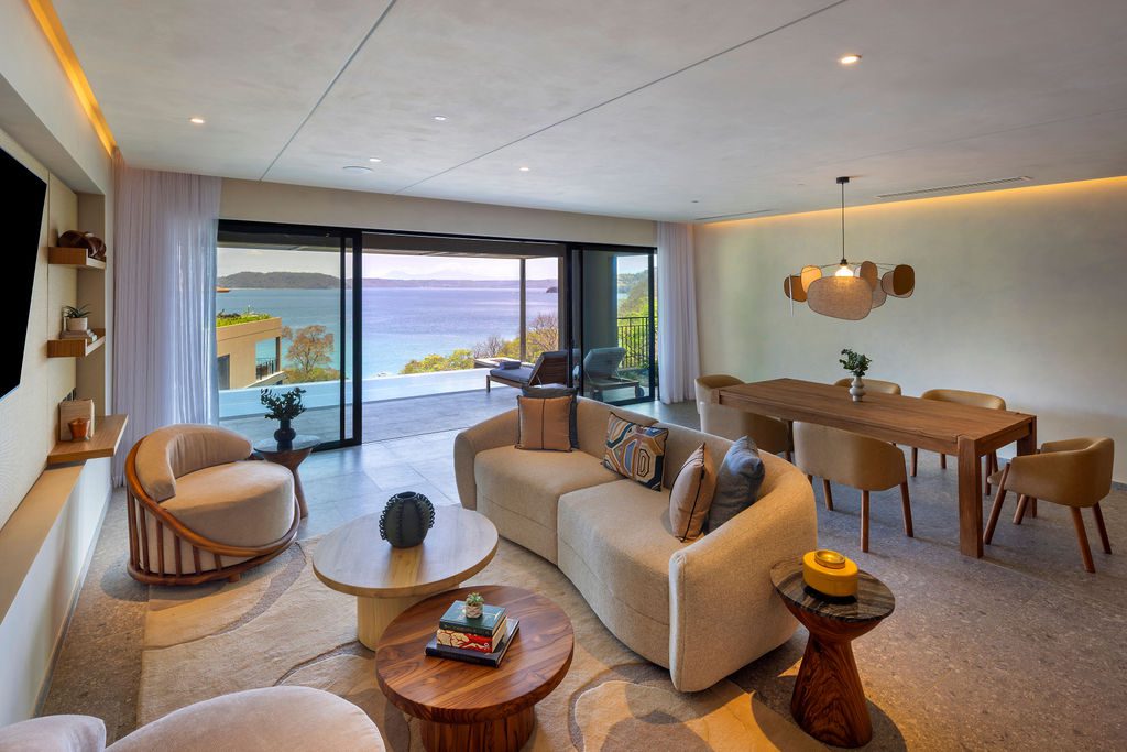 Luxury suite interior at Waldorf Astoria Costa Rica, with ocean view, curved sofa, and dining area.