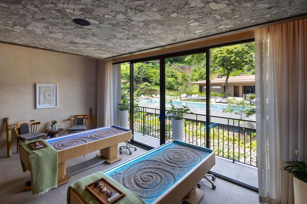 Luxury spa room at Waldorf Astoria Costa Rica with sand massage tables overlooking a pool.