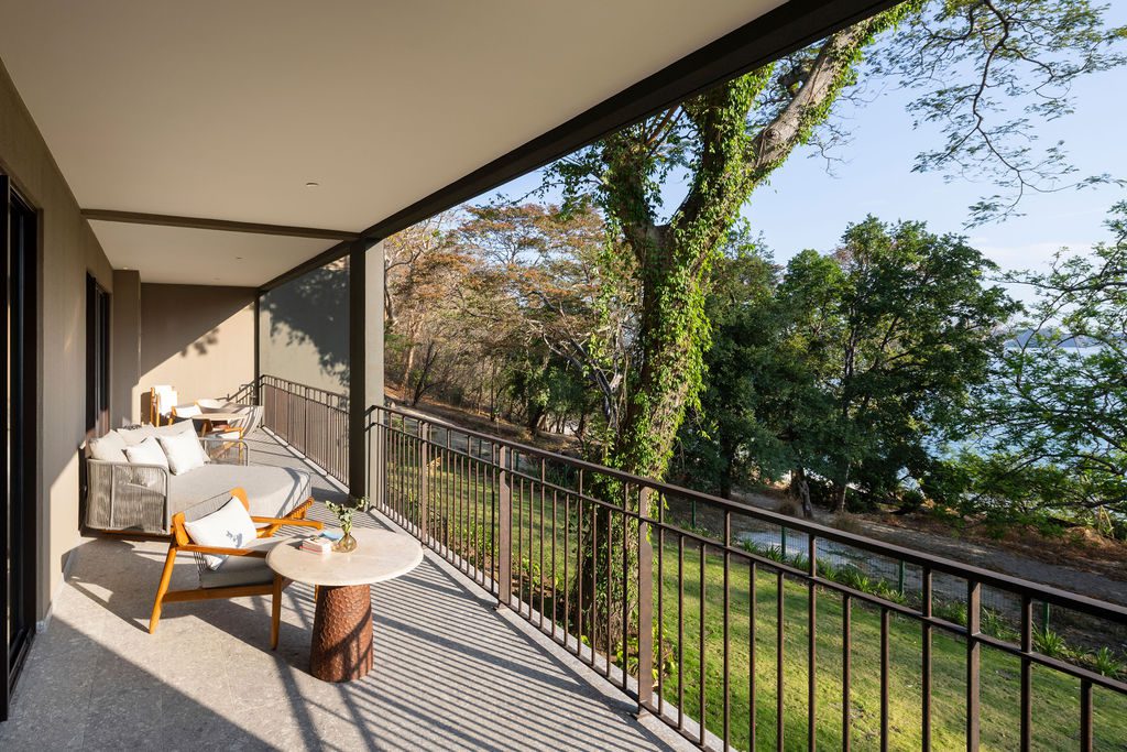 Waldorf Astoria Costa Rica balcony view with seating, railing, and lush green trees.