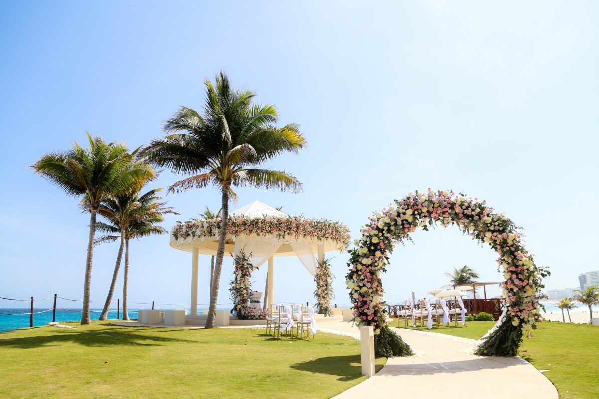 Luxury wedding venue in Cancun at Hyatt Ziva, with floral archway and gazebo on green lawn overlooking the ocean.