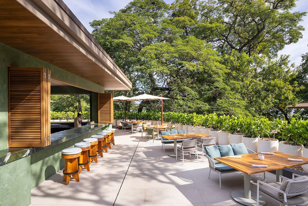 Outdoor dining at Waldorf Astoria Costa Rica with bar, tables, and lush greenery.