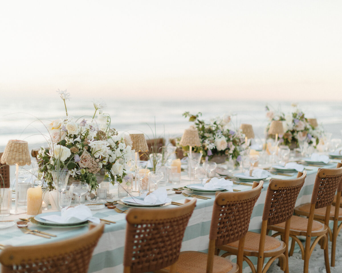 Beach wedding reception at an exclusive Punta Cana resort, featuring floral centerpieces and rattan chairs.