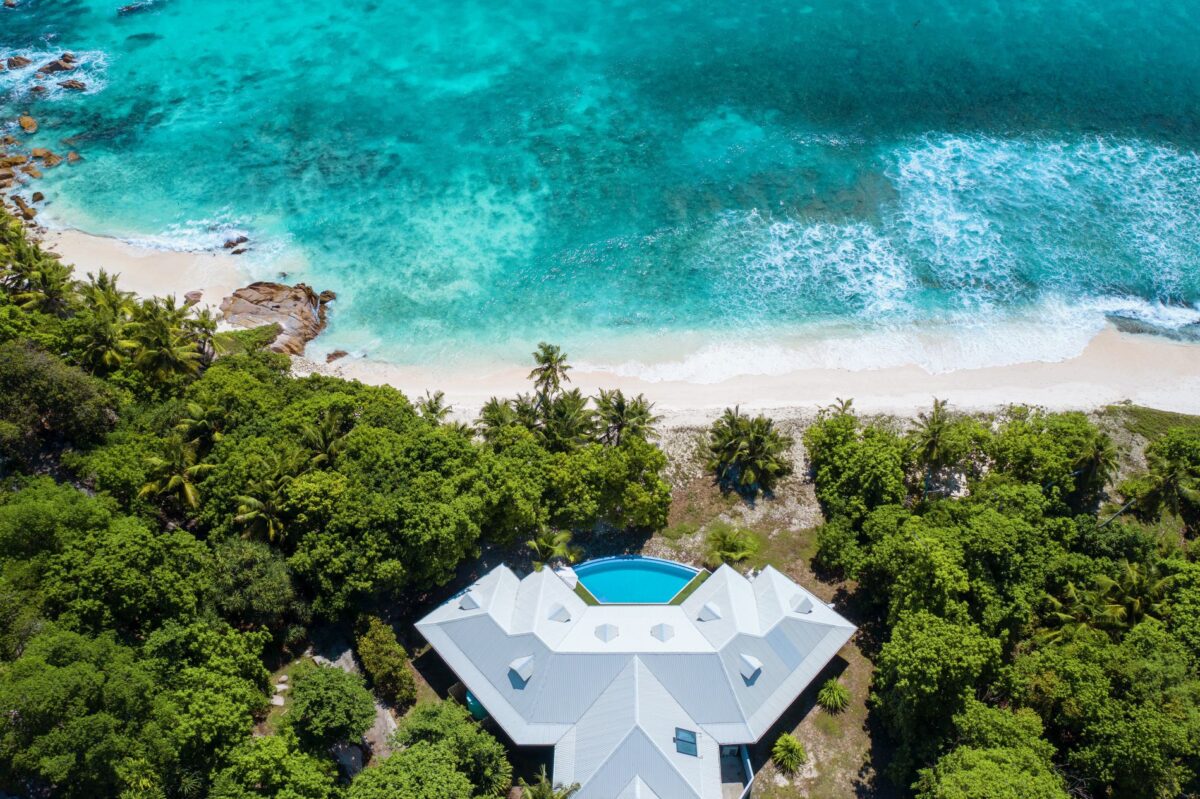Luxury villa rental with a pool overlooking a turquoise ocean and white sand beach.