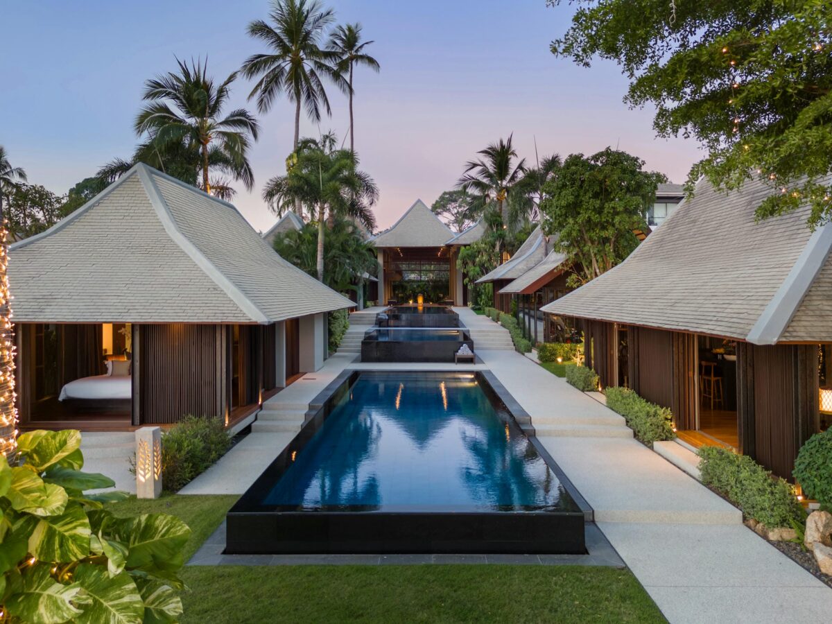 Luxury villa rental: Tranquil pool and villas at dusk surrounded by tropical greenery.