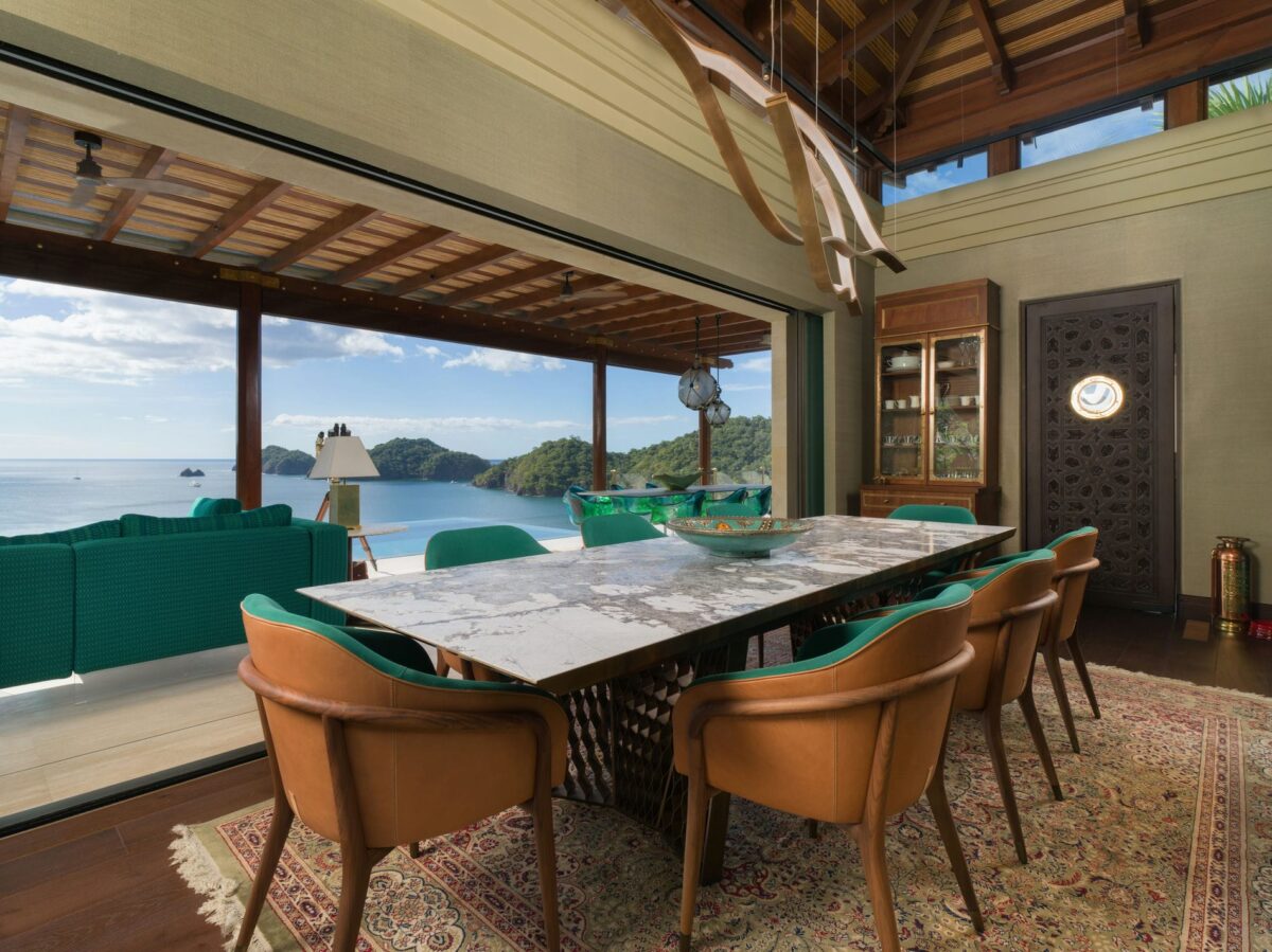 Luxury villa rentals dining area with ocean view, featuring a marble table and stylish seating.