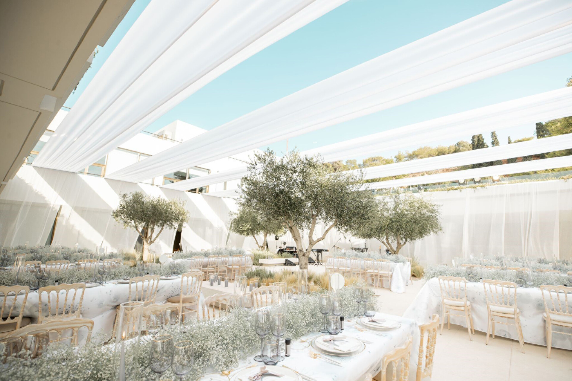 Elegant wedding reception at Four Seasons Astir Palace Hotel Athens, featuring draped fabric and olive trees.