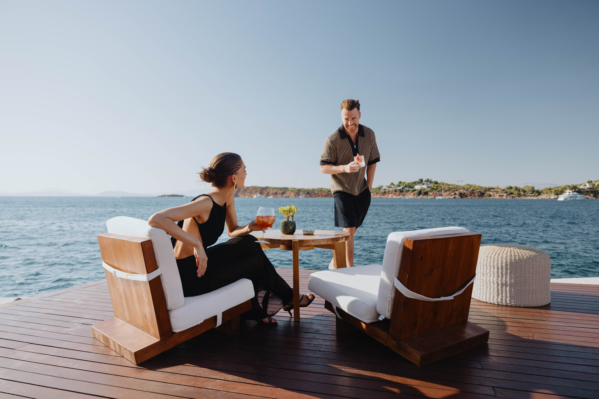 Couple enjoys drinks at Four Seasons Astir Palace Hotel, Athens, with sea view.