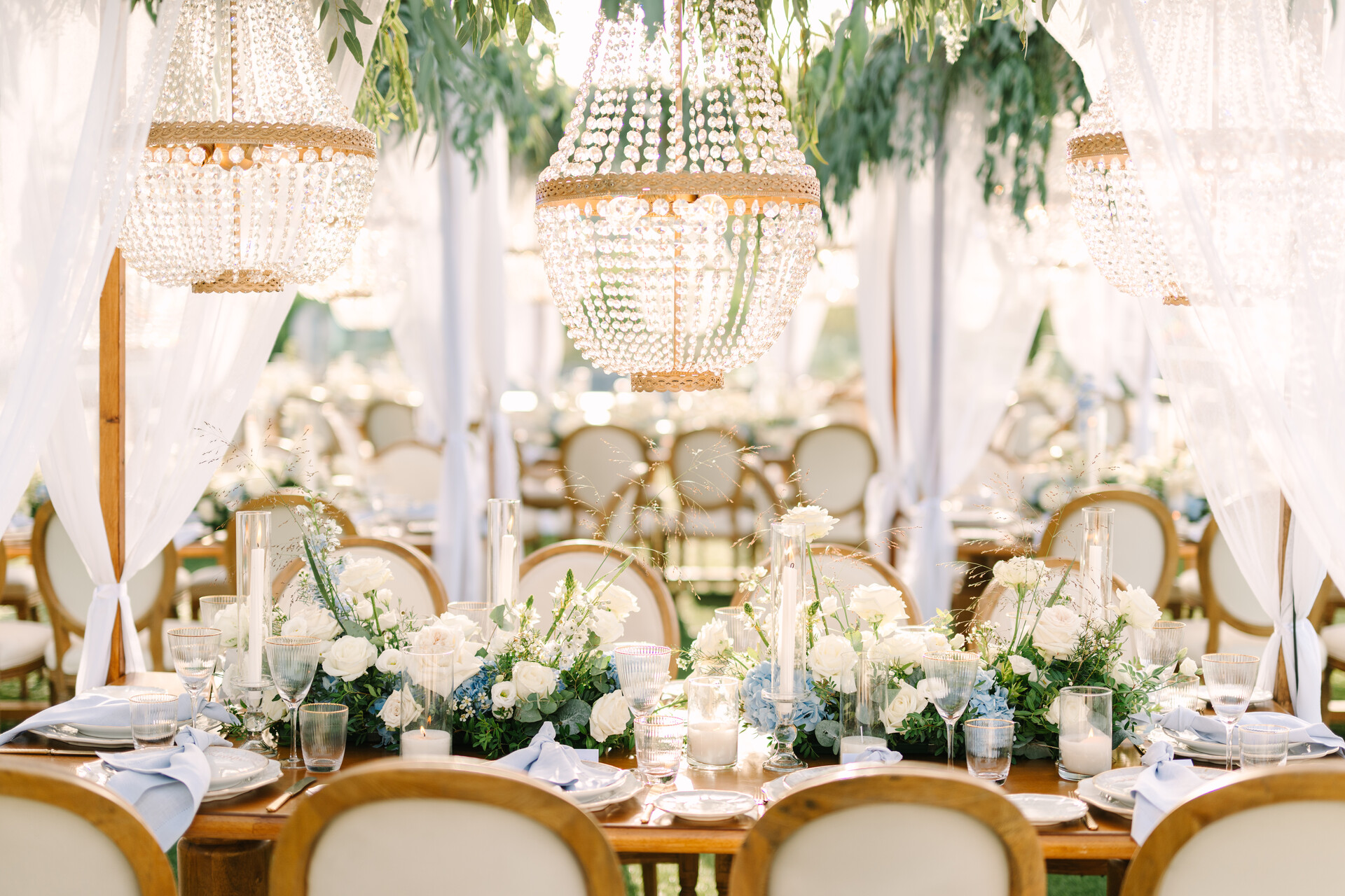 Elegant wedding reception setup at Four Seasons Astir Palace Athens with chandeliers and floral centerpieces.