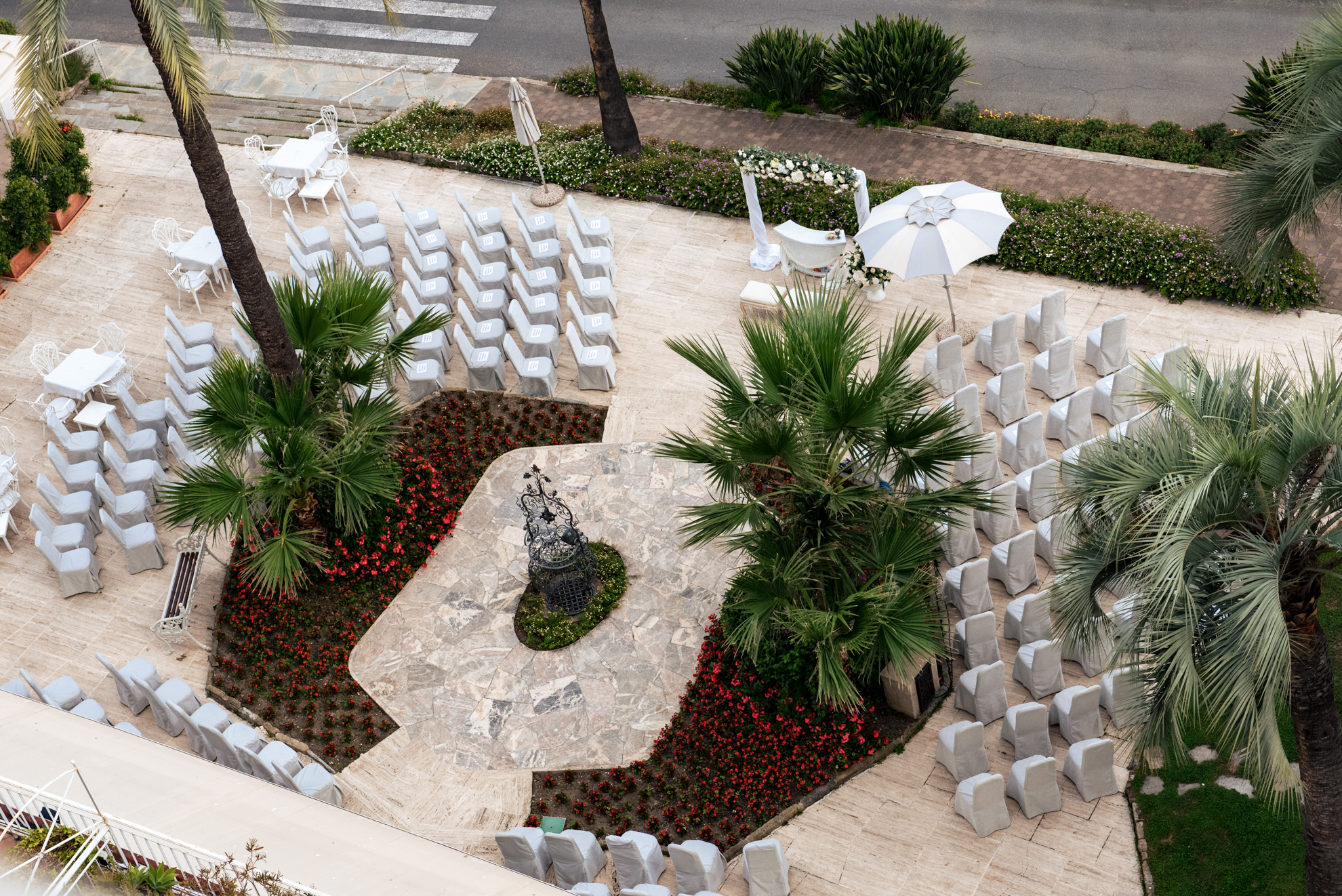 Wedding setup at Royal Hotel Sanremo, featuring rows of chairs, a decorated arch, and palm trees.