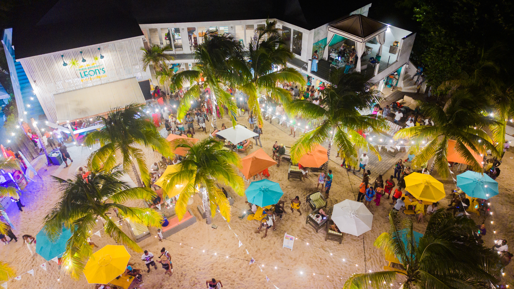 Beach party at Malliouhana resort with colorful umbrellas and string lights.