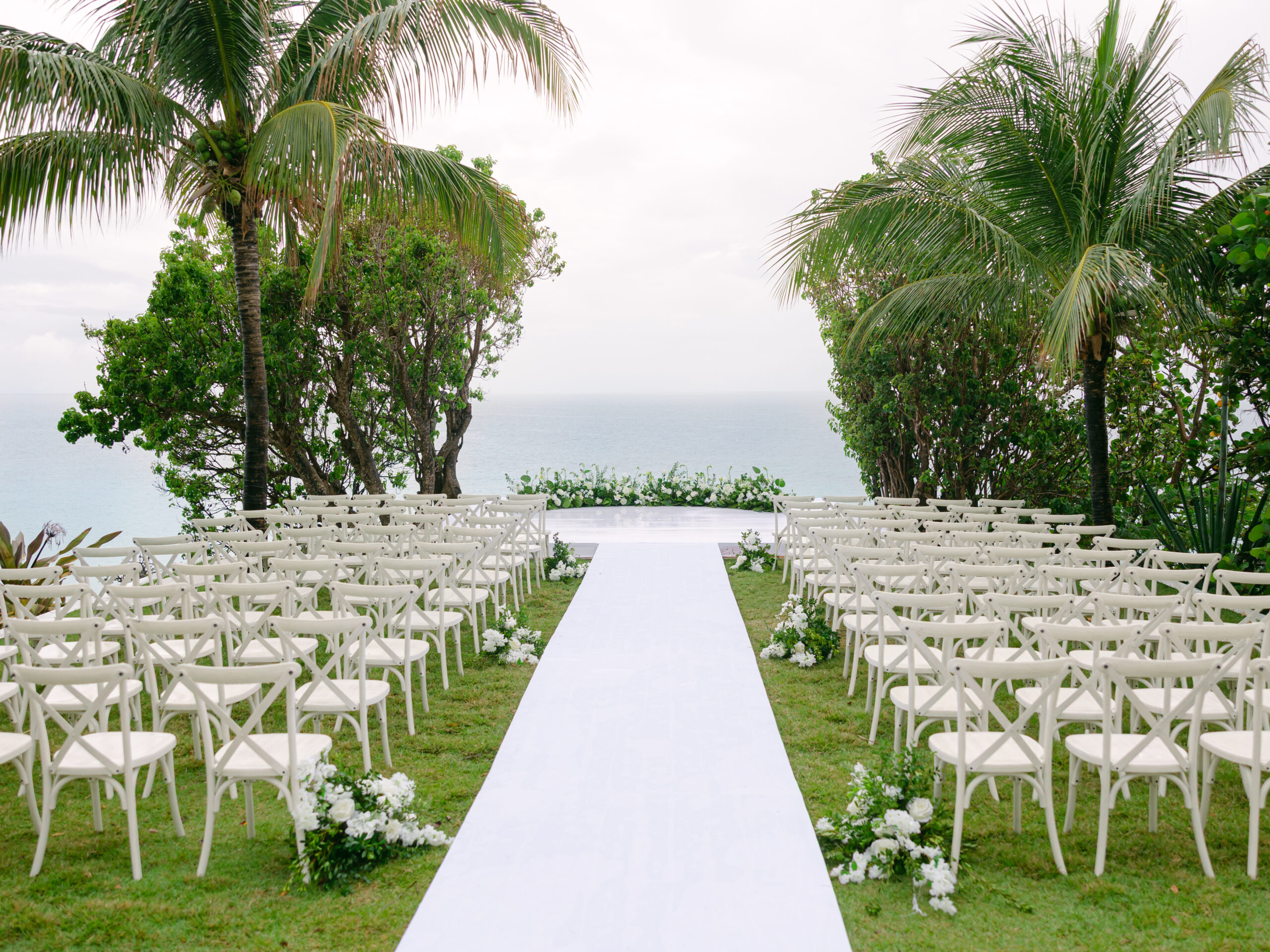Malliouhana wedding ceremony setup with white chairs and ocean view.