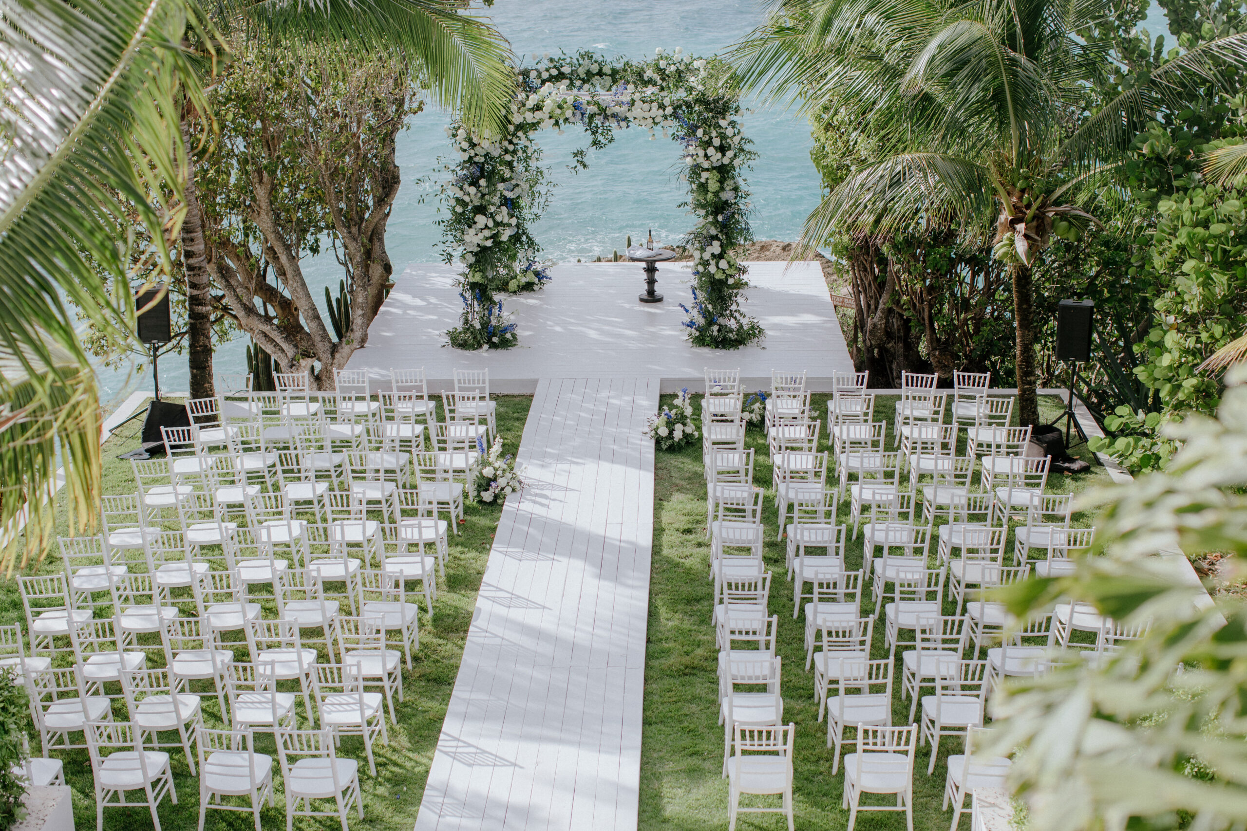 Malliouhana wedding ceremony setup with white chairs and floral arch.