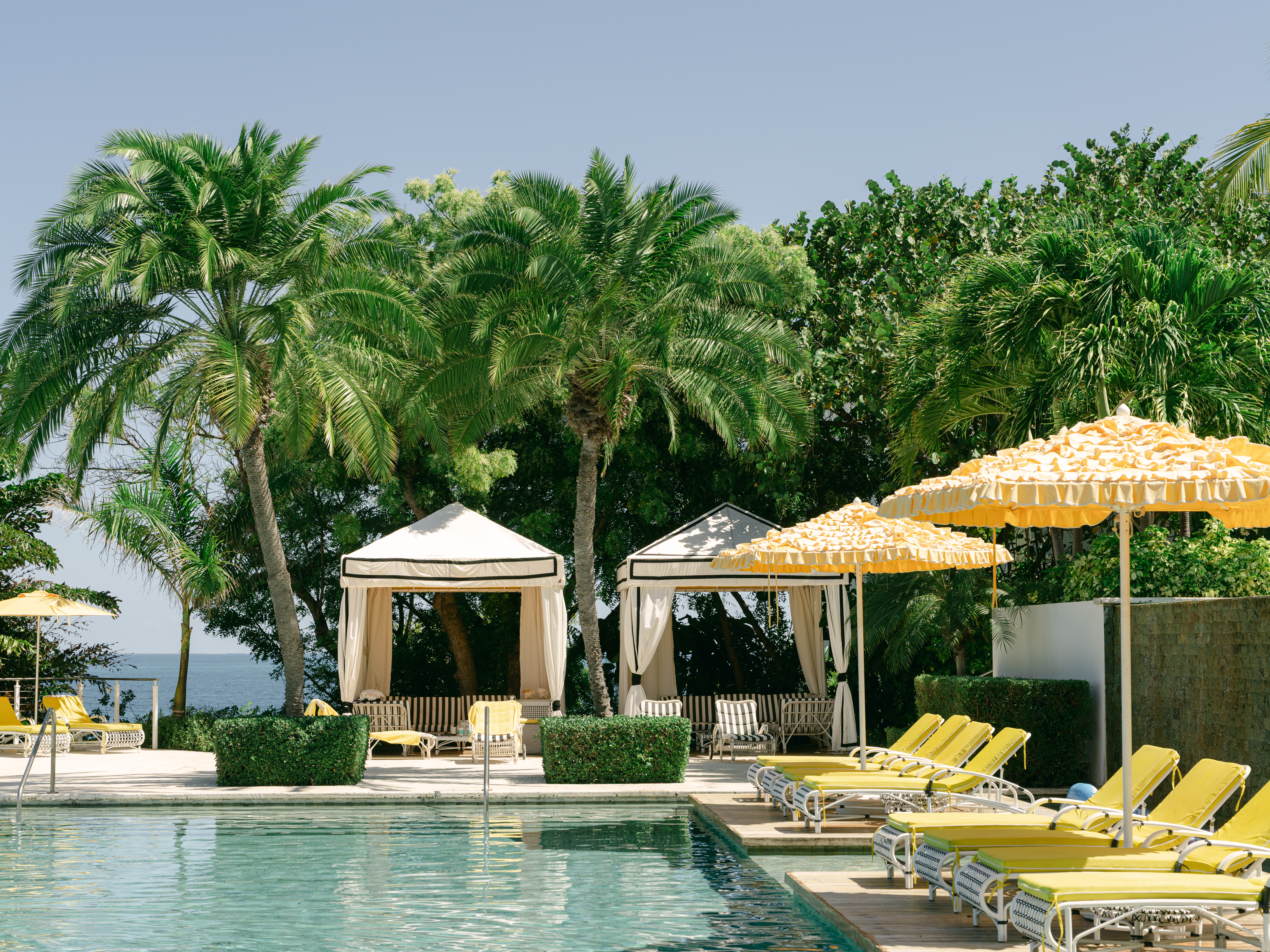 Tropical resort pool with palm trees and yellow lounge chairs