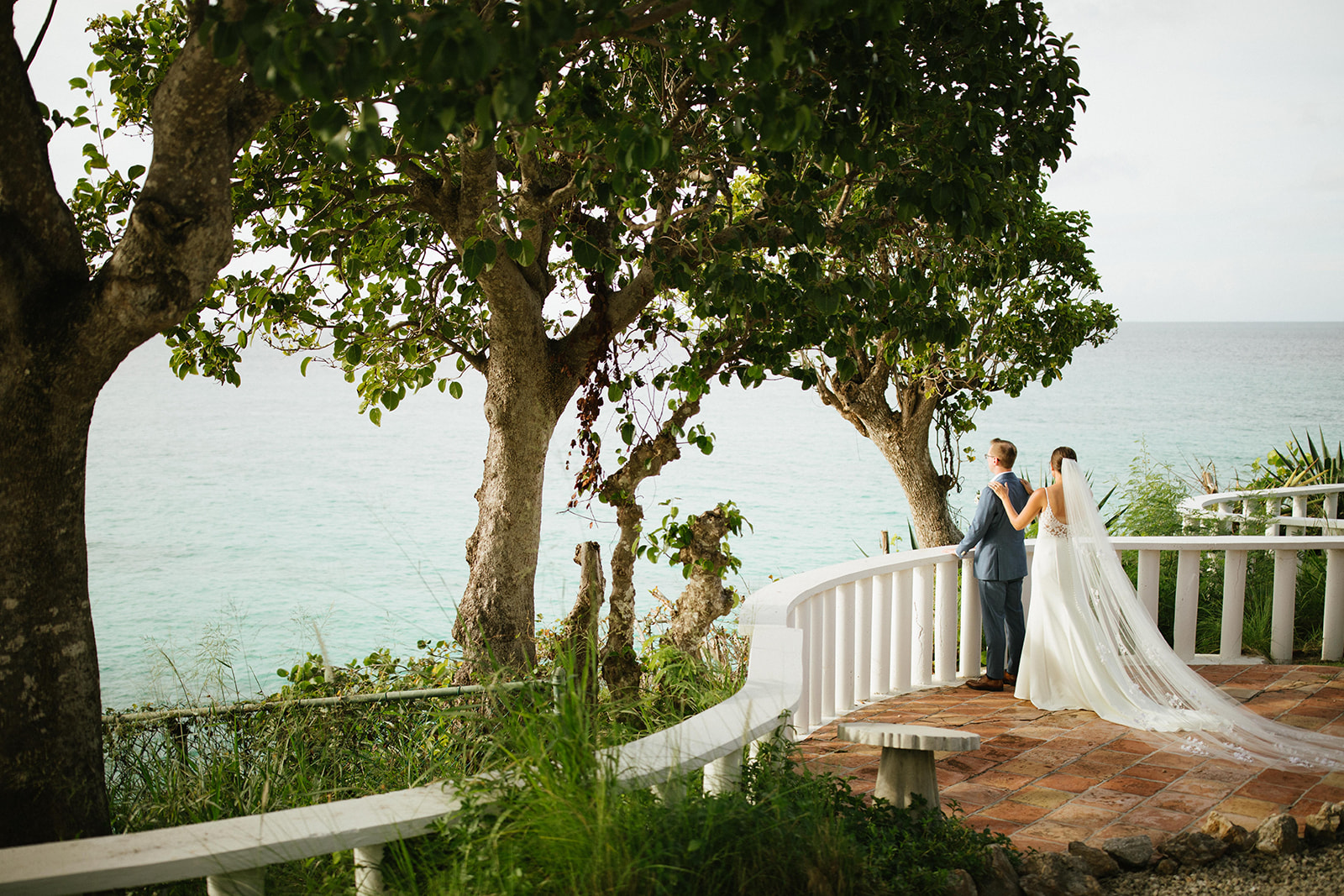 Bride and groom at Malliouhana resort overlook turquoise ocean. Wedding day view.