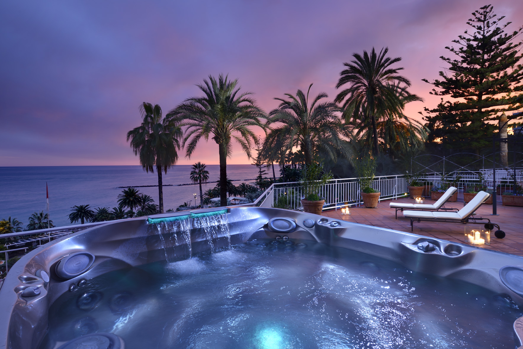 Hot tub at Royal Hotel Sanremo, a luxury wedding venue, with ocean and palm tree views at sunset.