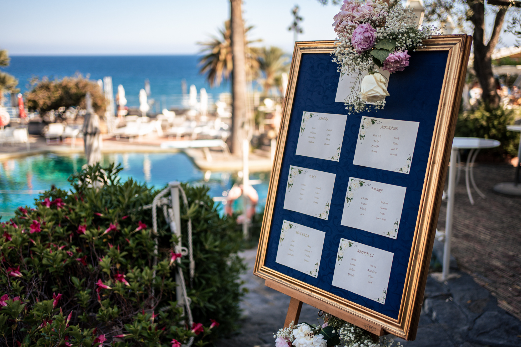 Wedding seating chart at Royal Hotel Sanremo, luxury wedding venue, with pool and sea view in background.