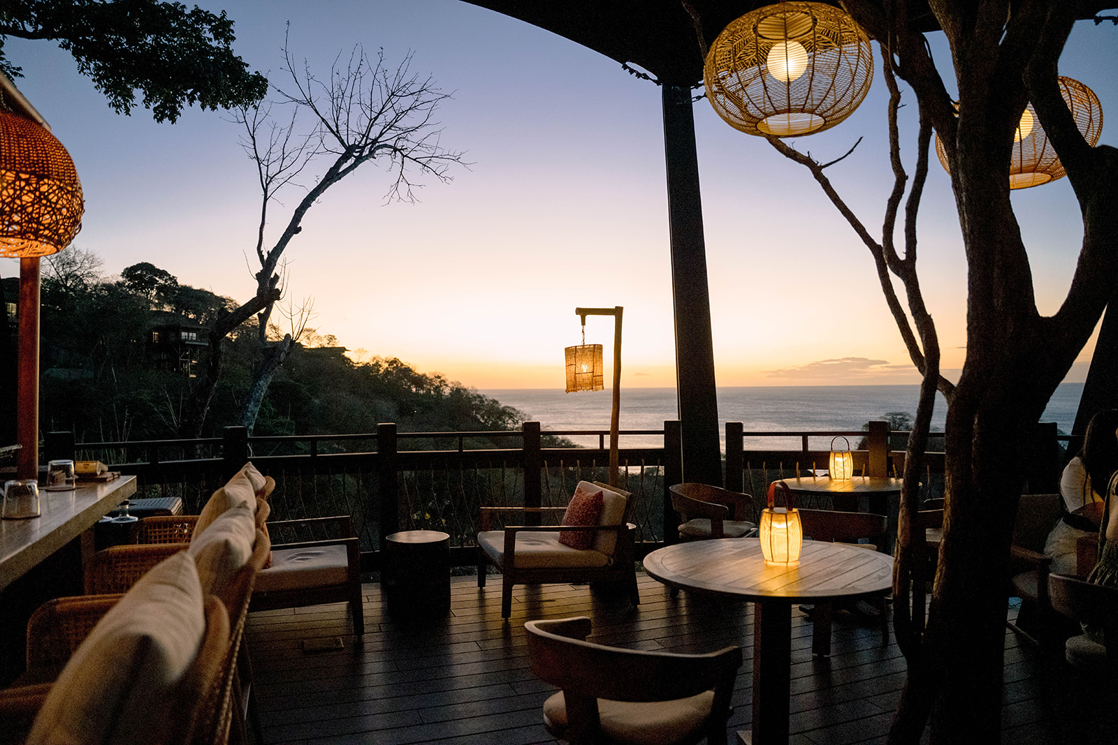 Sunset view from Nekajui, a Ritz-Carlton Reserve, with outdoor seating and wicker lanterns.