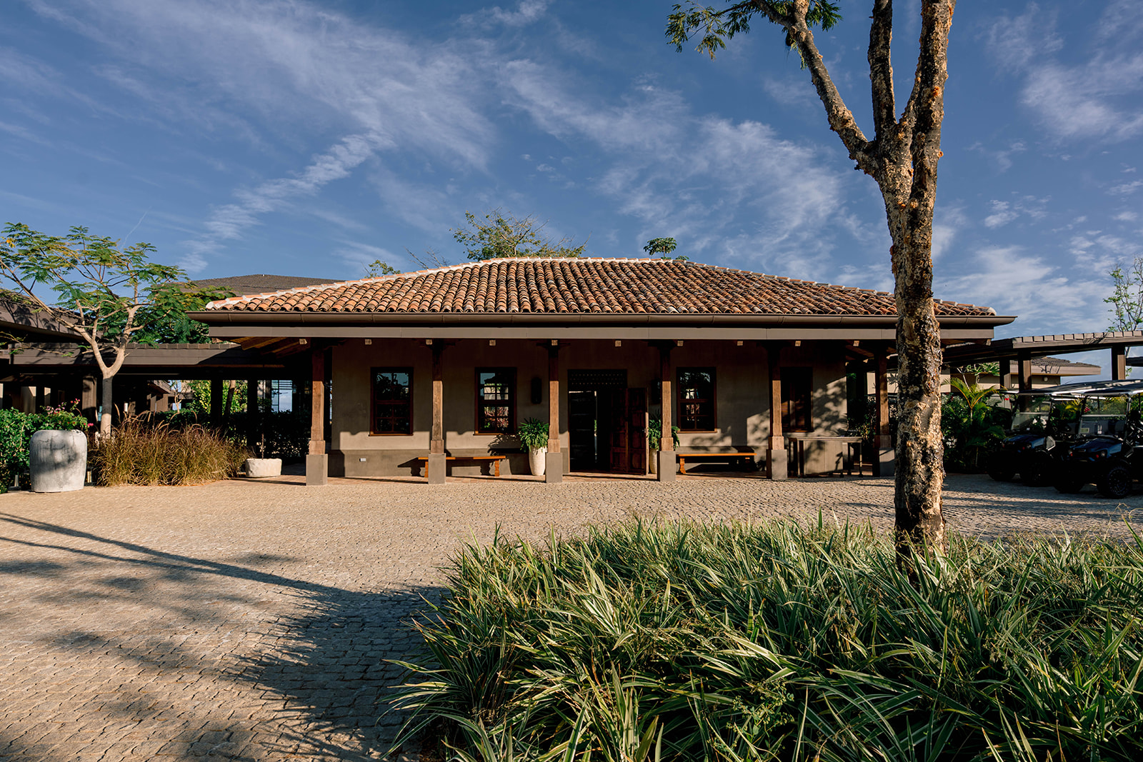 Nekajui, a Ritz Carlton Reserve building with a terracotta tile roof and stone exterior under a blue sky.