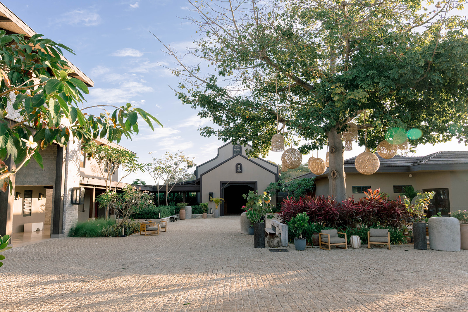 Nekajui Ritz Carlton Reserve entrance with stone pathway, lush greenery, and hanging lanterns.