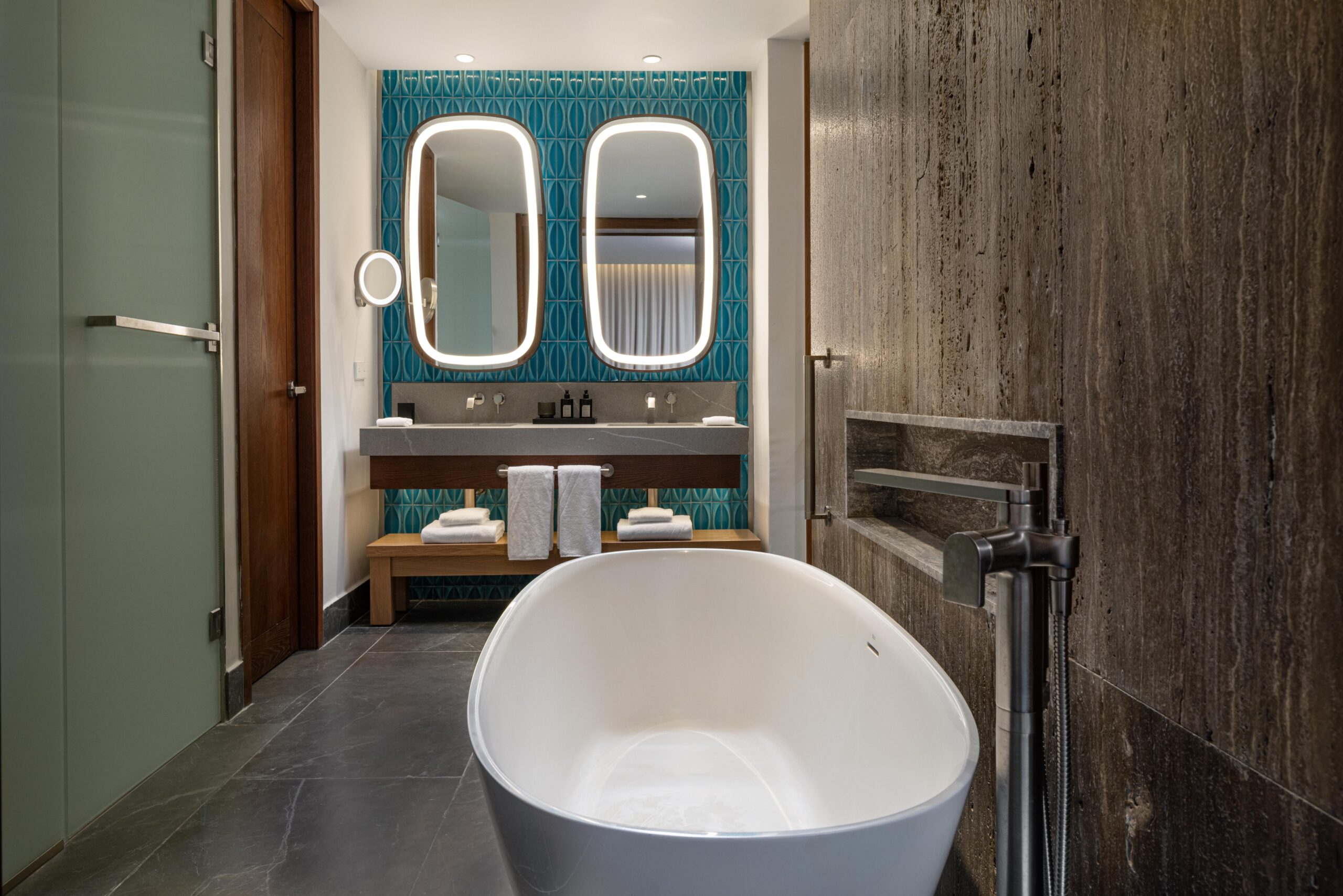 Modern bathroom at W Punta Cana with a freestanding tub, double vanity, and stylish blue tile.