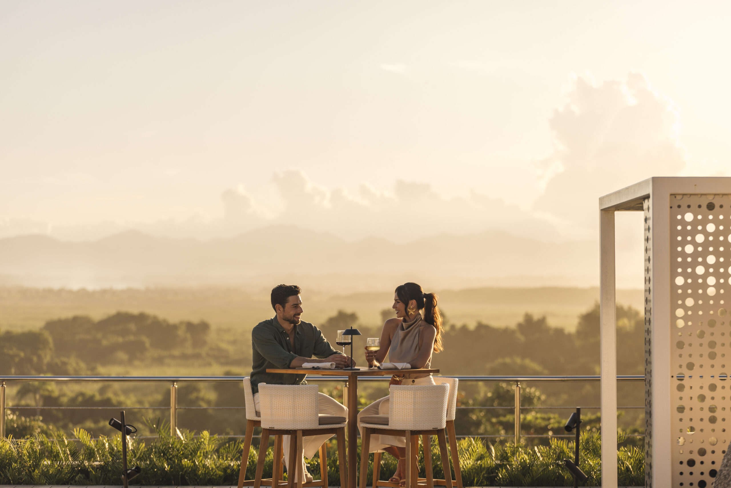 Couple enjoying drinks at W Punta Cana with a scenic mountain view.