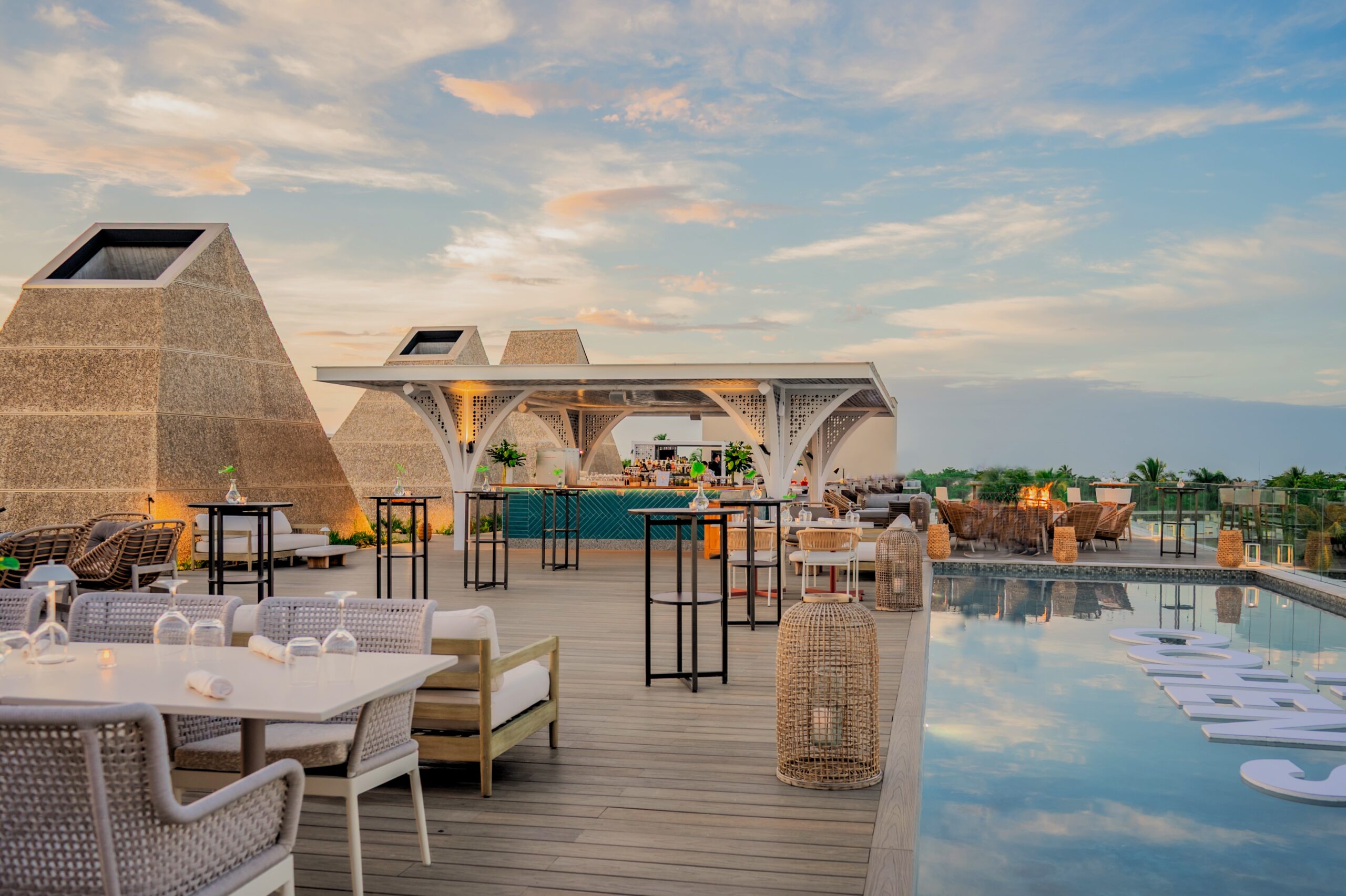 W Punta Cana rooftop bar with pool, tables, and unique architectural design at sunset.