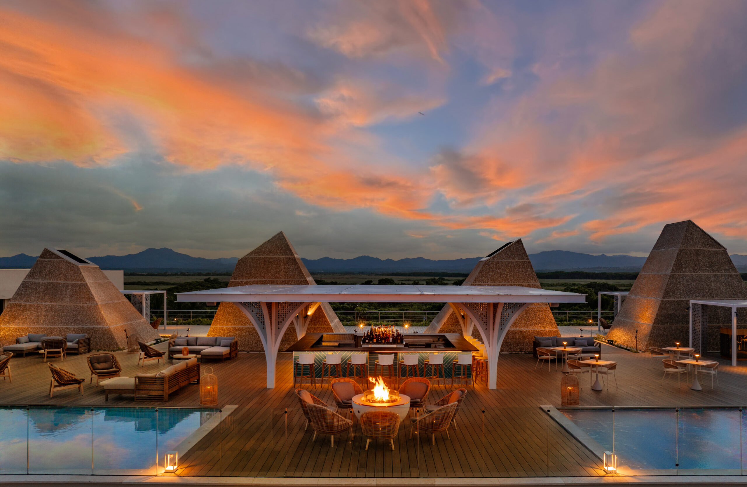 W Punta Cana rooftop bar at sunset, with pools and pyramid-shaped structures.
