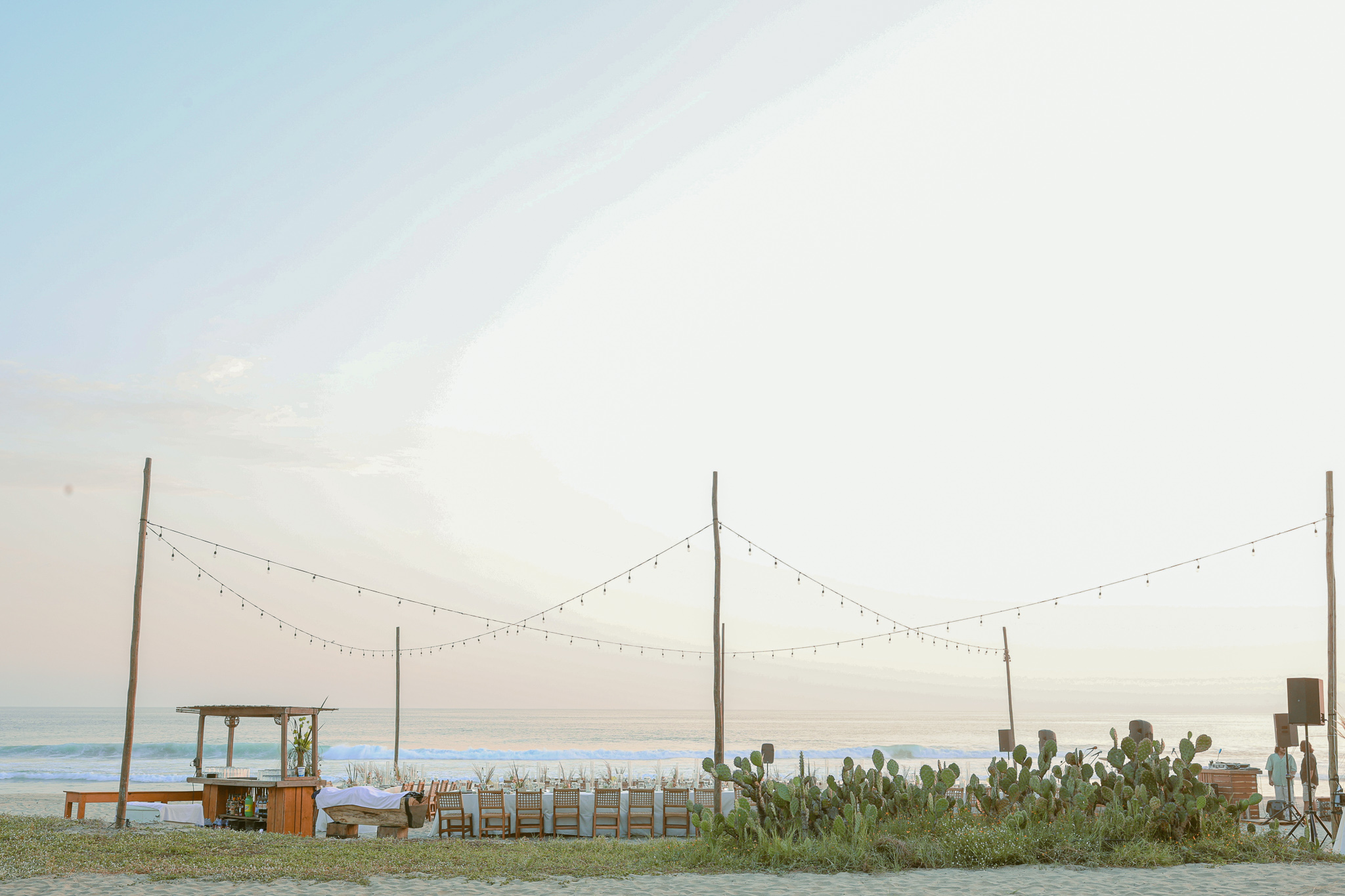 Beach wedding setup with tables, chairs, and string lights at Hotel Casa Yuma