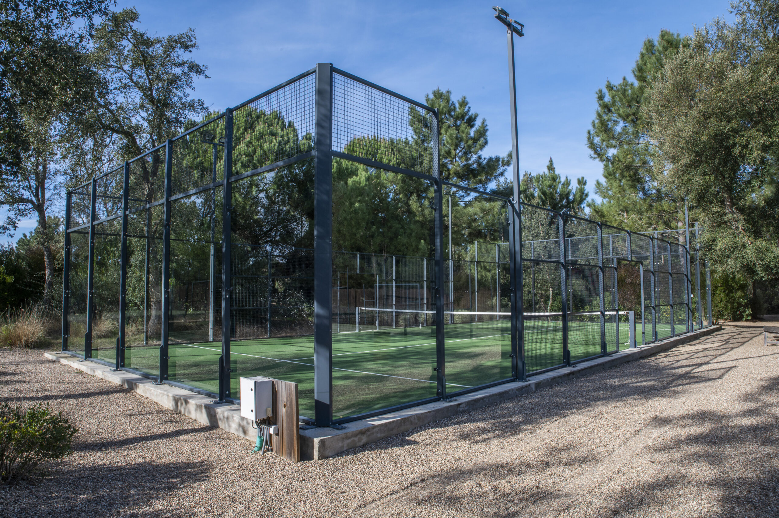 Padel tennis court surrounded by trees under a blue sky