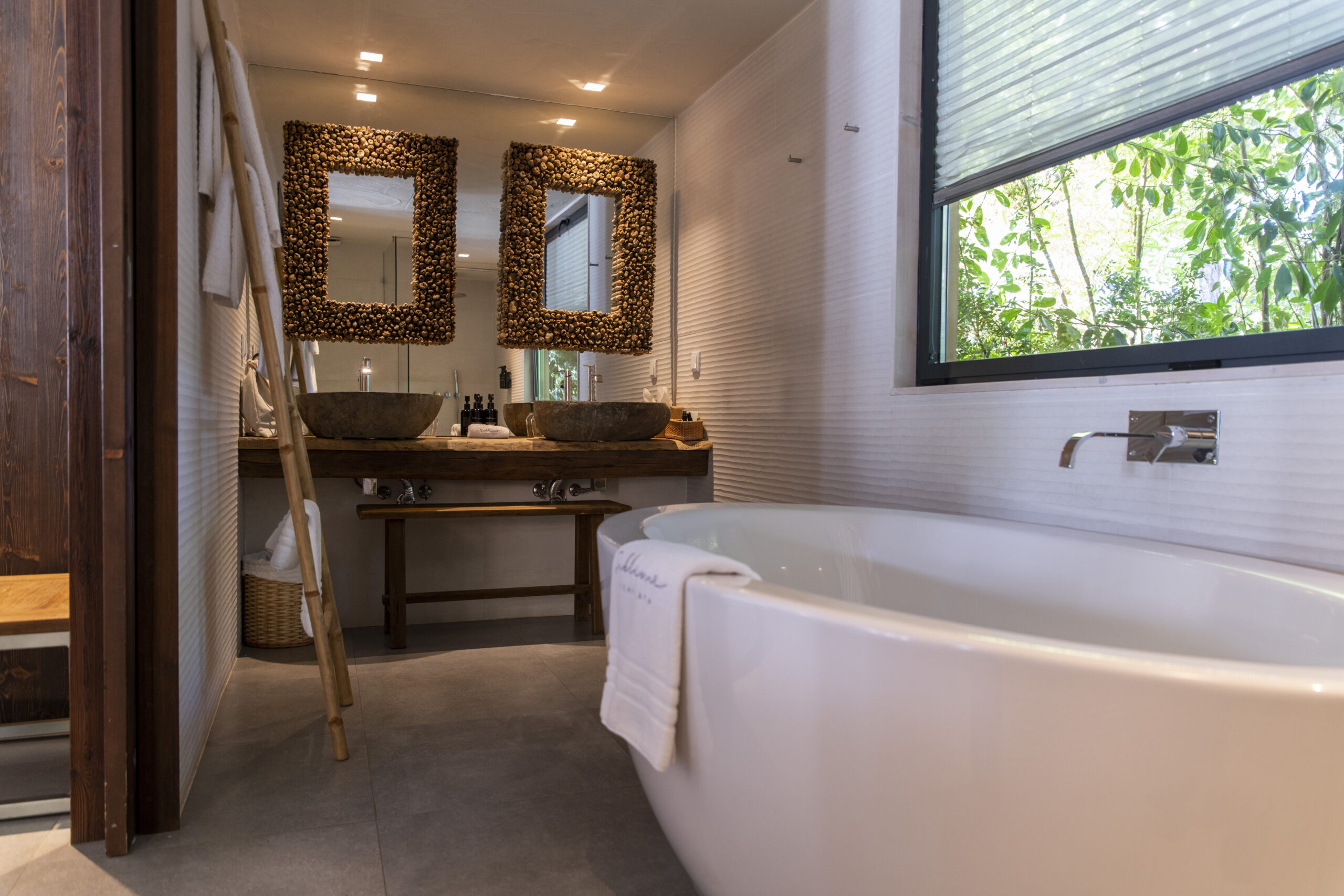 Luxurious bathroom with freestanding tub, double stone sinks, and natural light