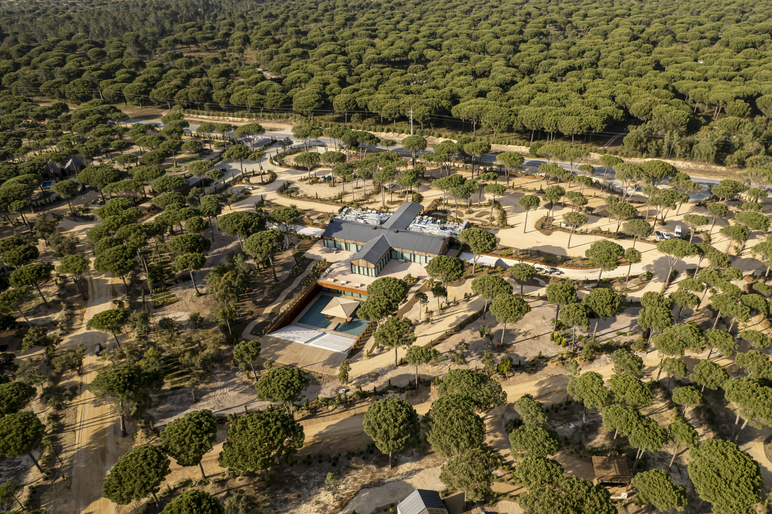 Aerial view of Sublime Comporta resort nestled in a pine forest with a pool.