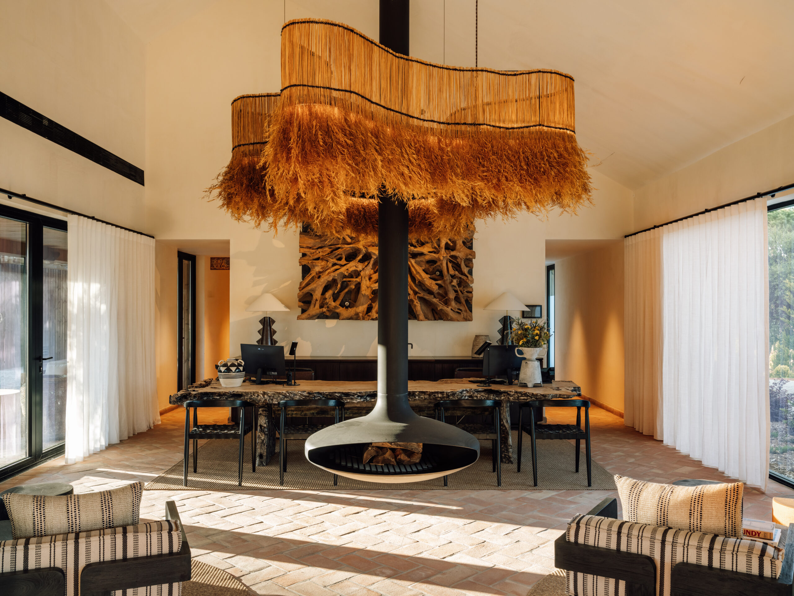Modern living room with suspended fireplace, natural wood table, and unique lighting