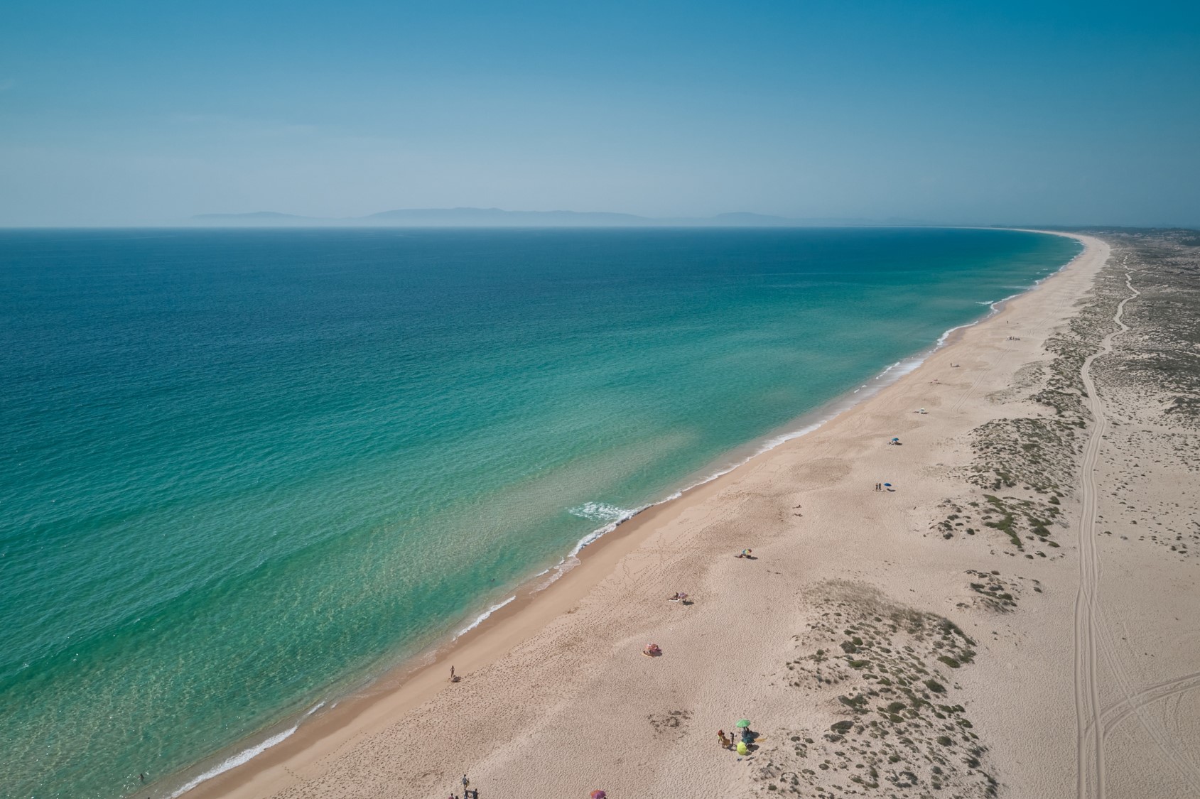 Aerial view of a long, sandy beach with turquoise water in Comporta, Portugal